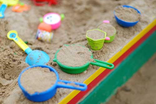 Tavistock Preschool | About us - image of a sand pit with lots of plastic pans full of sand