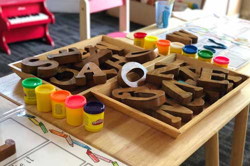 Tavistock Preschool | Home - image of playdoh and wooden letters on a desk