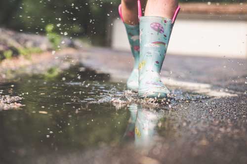 Tavistock Preschool | Home - image of child wearing wellies walking in puddles